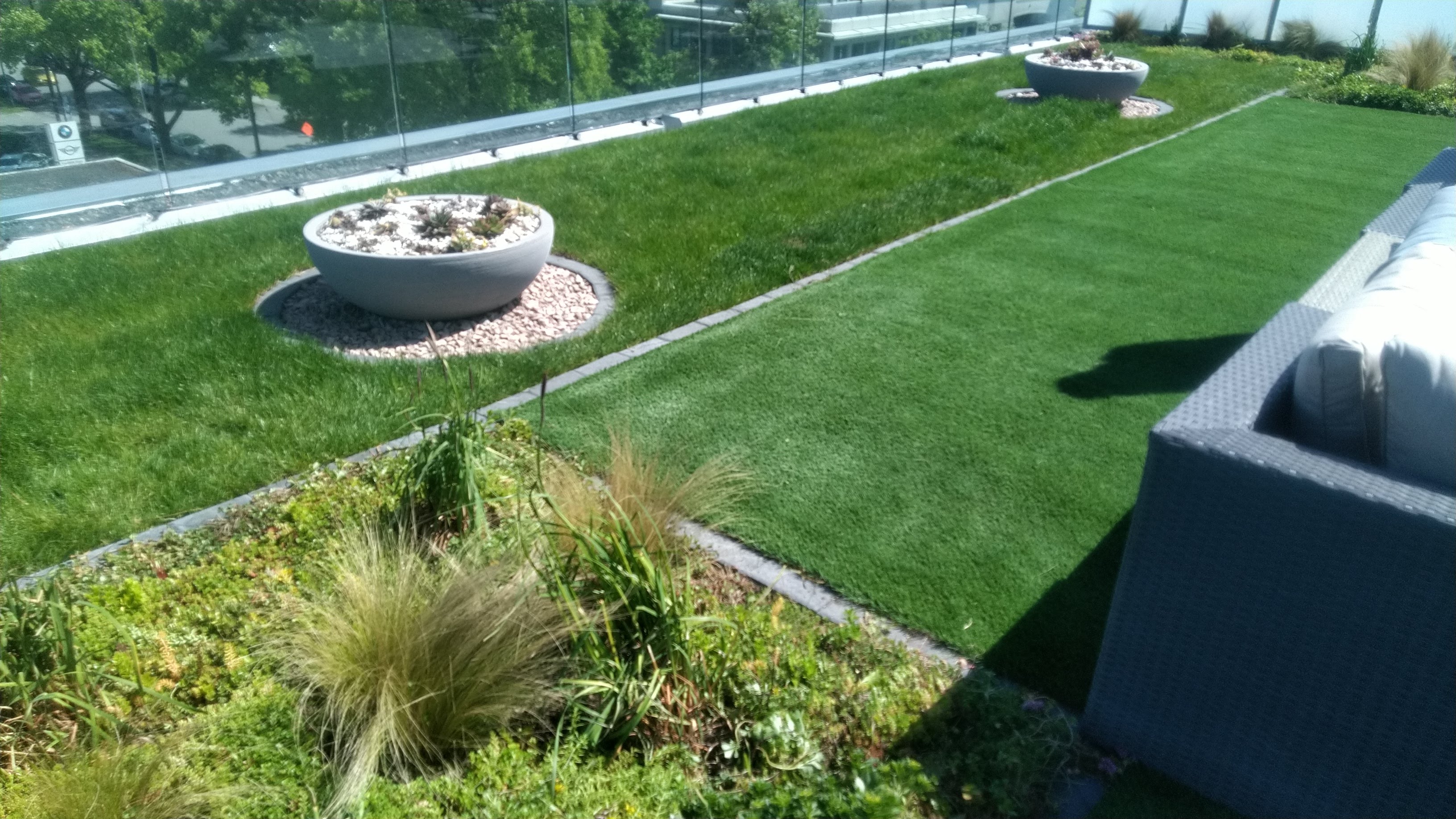 real grass and artificial turf with flower beds and pots